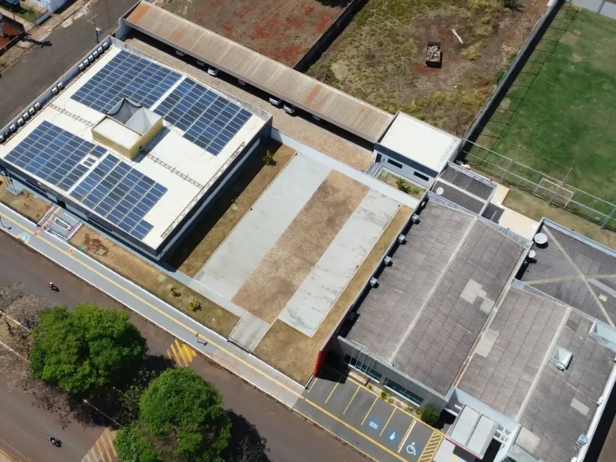 Módulos fotovoltaicos na laje de cobertura de uma edificação de ensino, vista aérea.