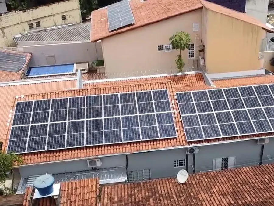 Dois arranjos de módulos fotovoltaicos em telhado cerâmico de uma residência.